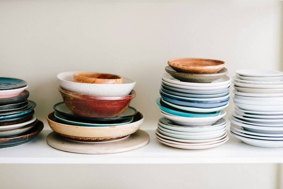 Stylish ceramic dinnerware set on a rustic wooden table with linen napkins and natural light